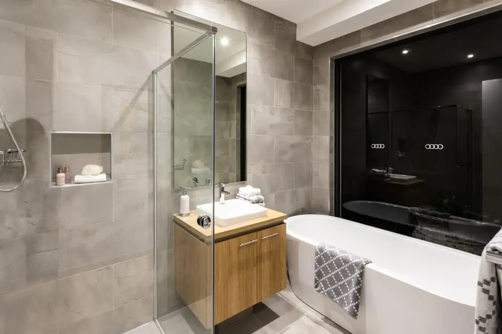 Modern bathroom with a shower and bathtub next to a mirror and tap with washstand illuminated at night