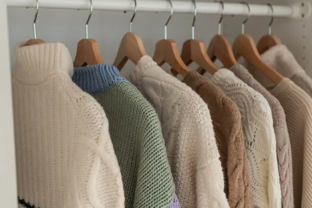 Warm winter beige wool pullover and knitwear and hanging in wardrobe