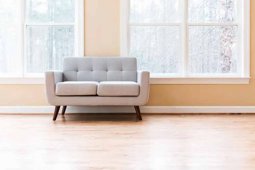 Luxury interior with grey loveseat in front of windows